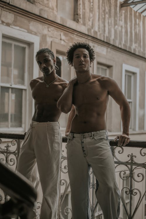 Young Shirtless Men Standing on a Balcony 