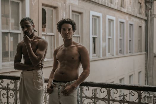 Young Shirtless Men Standing on a Balcony 