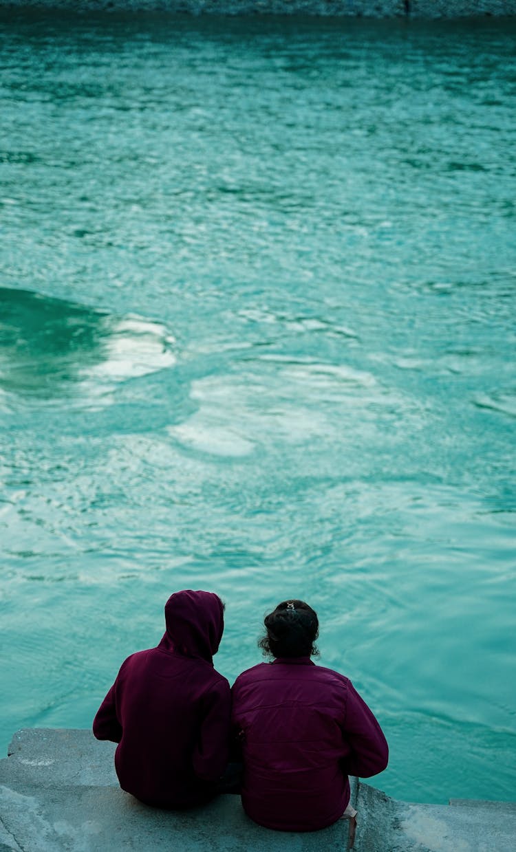 Two People Sitting And Looking At The Sea