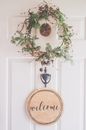 Photo of a White Door With a Hanging Wreath and Welcome Decor