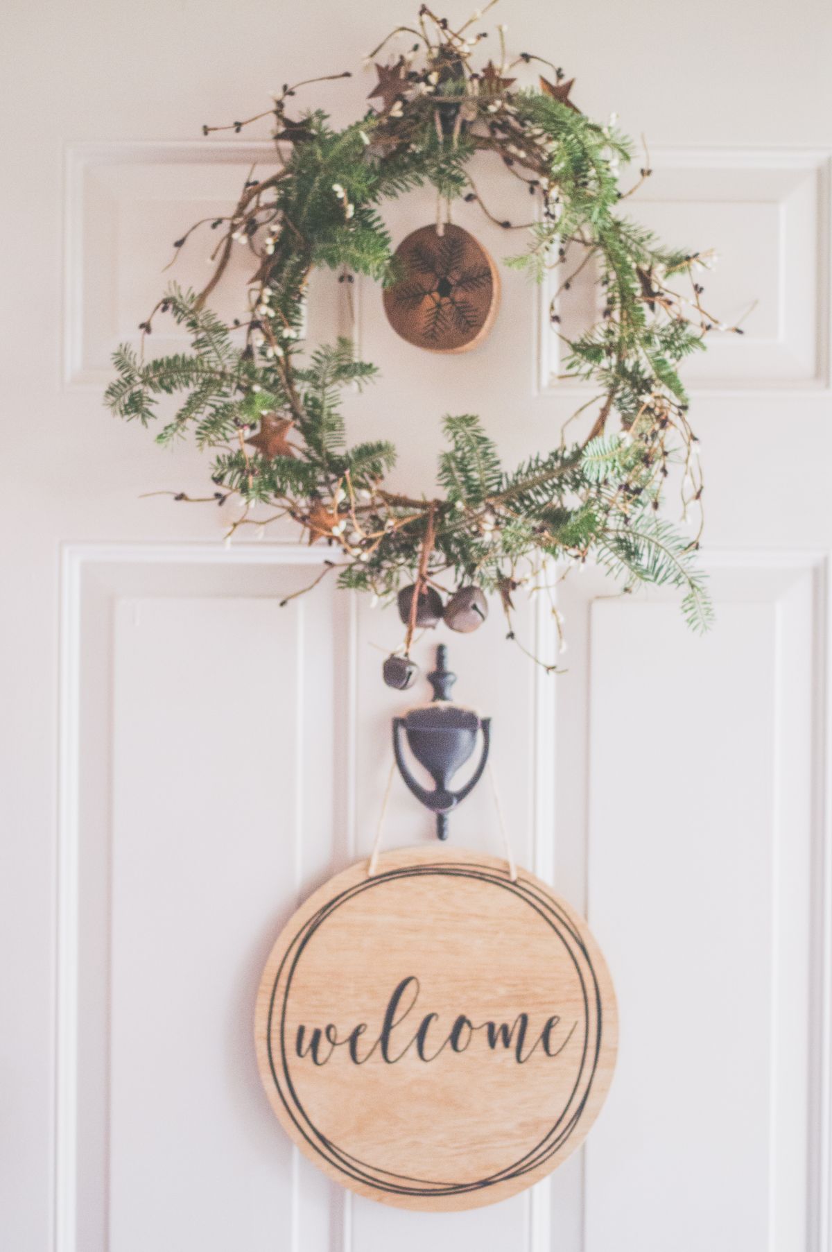 Rustic wreath with a welcome sign on a white front door