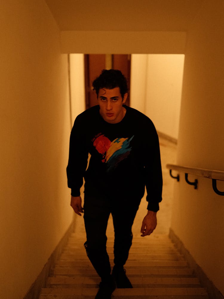 Young Man Walking Up The Stairs In A Hall 