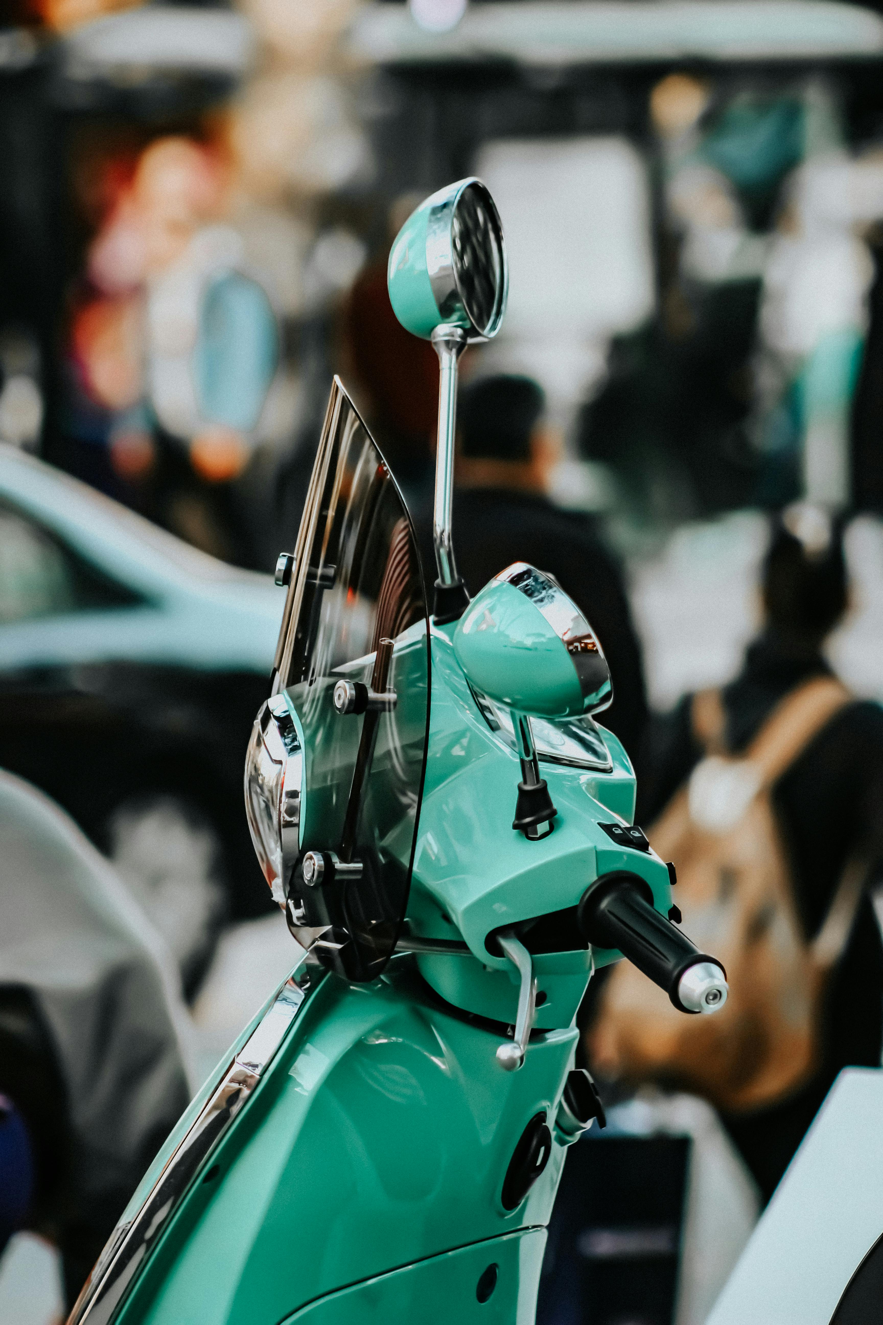 Free Light green Vespa scooter with windshield in busy urban street scene. Stock Photo