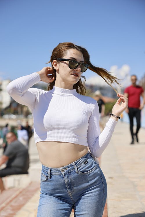 Young Woman in a Casual Outfit and Sunglasses Posing Outdoors 