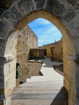Sunlit stone archway leading to historic ruins in Zamora, Spain.