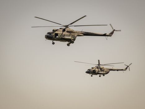 Two military helicopters flying over clear skies, showcasing aviation power.