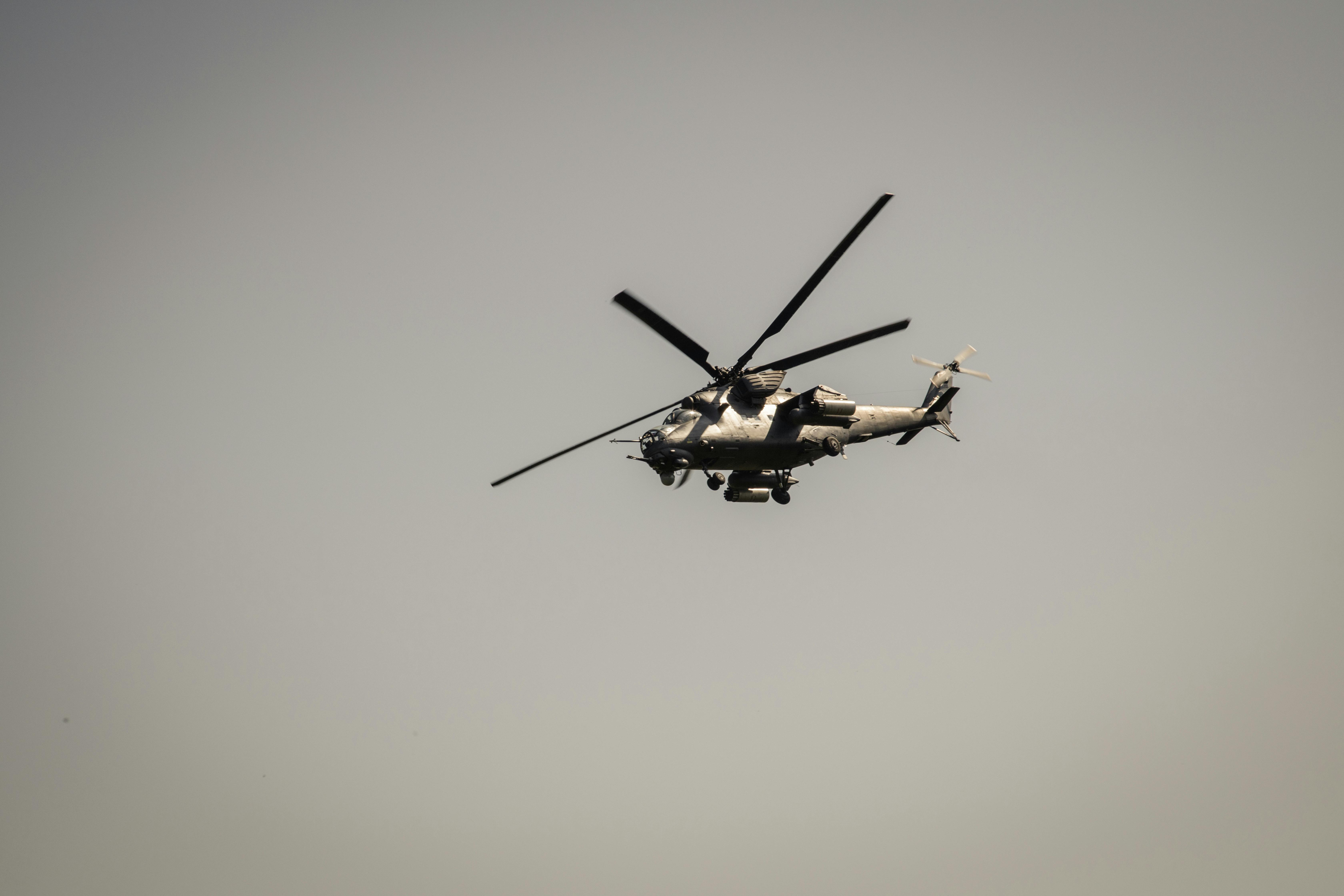 A military attack helicopter flying against a gray sky, showcasing defense technology.