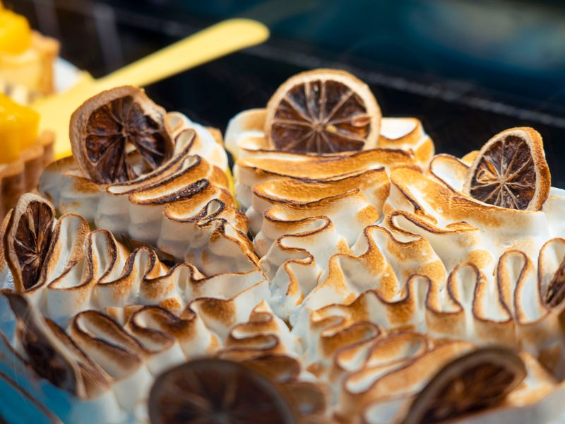 Close-up of a beautifully crafted lemon meringue tart with toasted peaks and dried lemon s