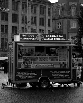 Black and white photo of a street food truck offering hot dogs and hamburgers in Amsterdam.
