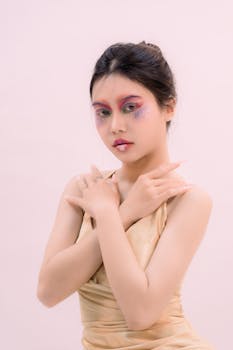 Artistic portrait of a woman with colorful eye makeup, posing elegantly in a studio setting.