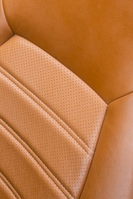 Detailed close-up of a classic car's vintage leather seat with rich texture and stitching. - Common Misconceptions About Handbag Care