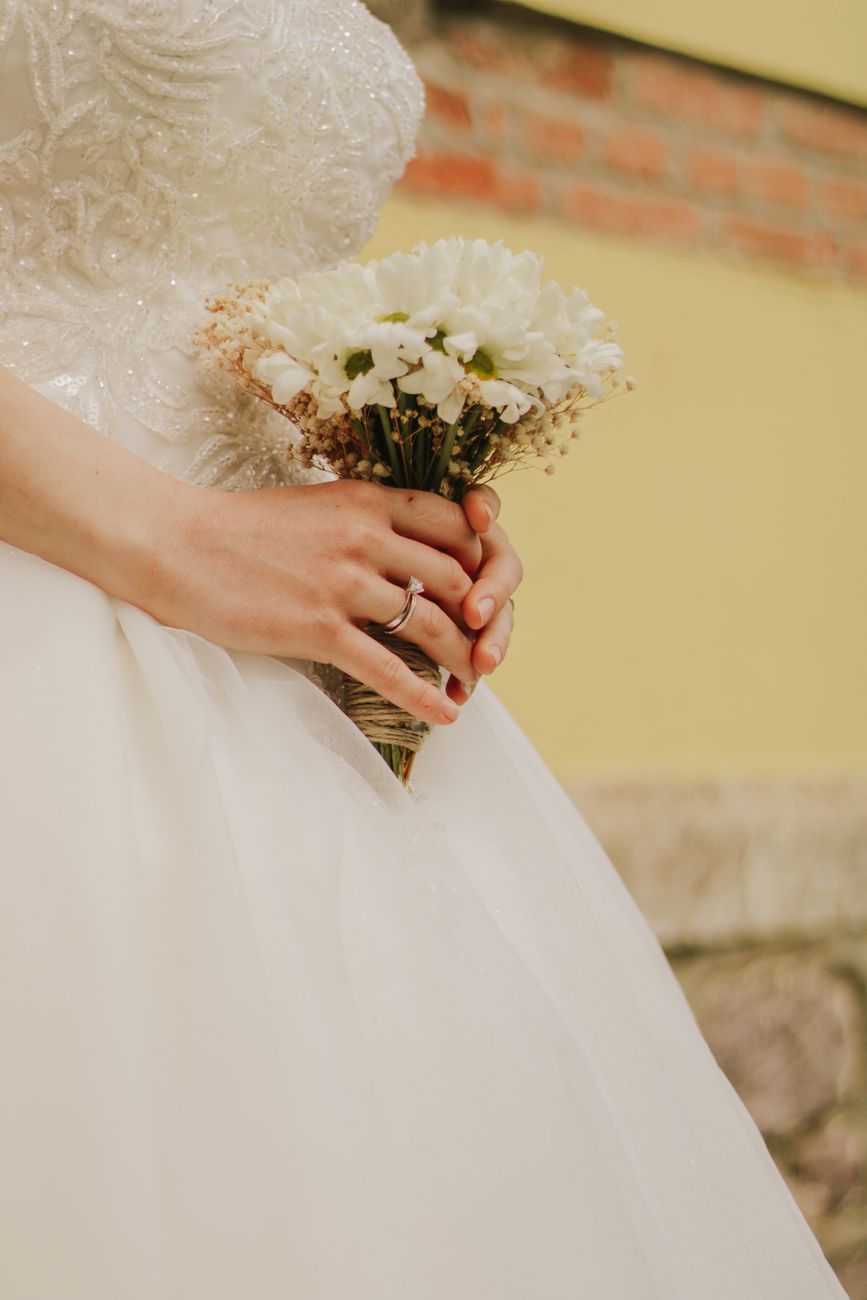 Close-up of a bride holding a white bouquet, showcasing wedding details and elegance.