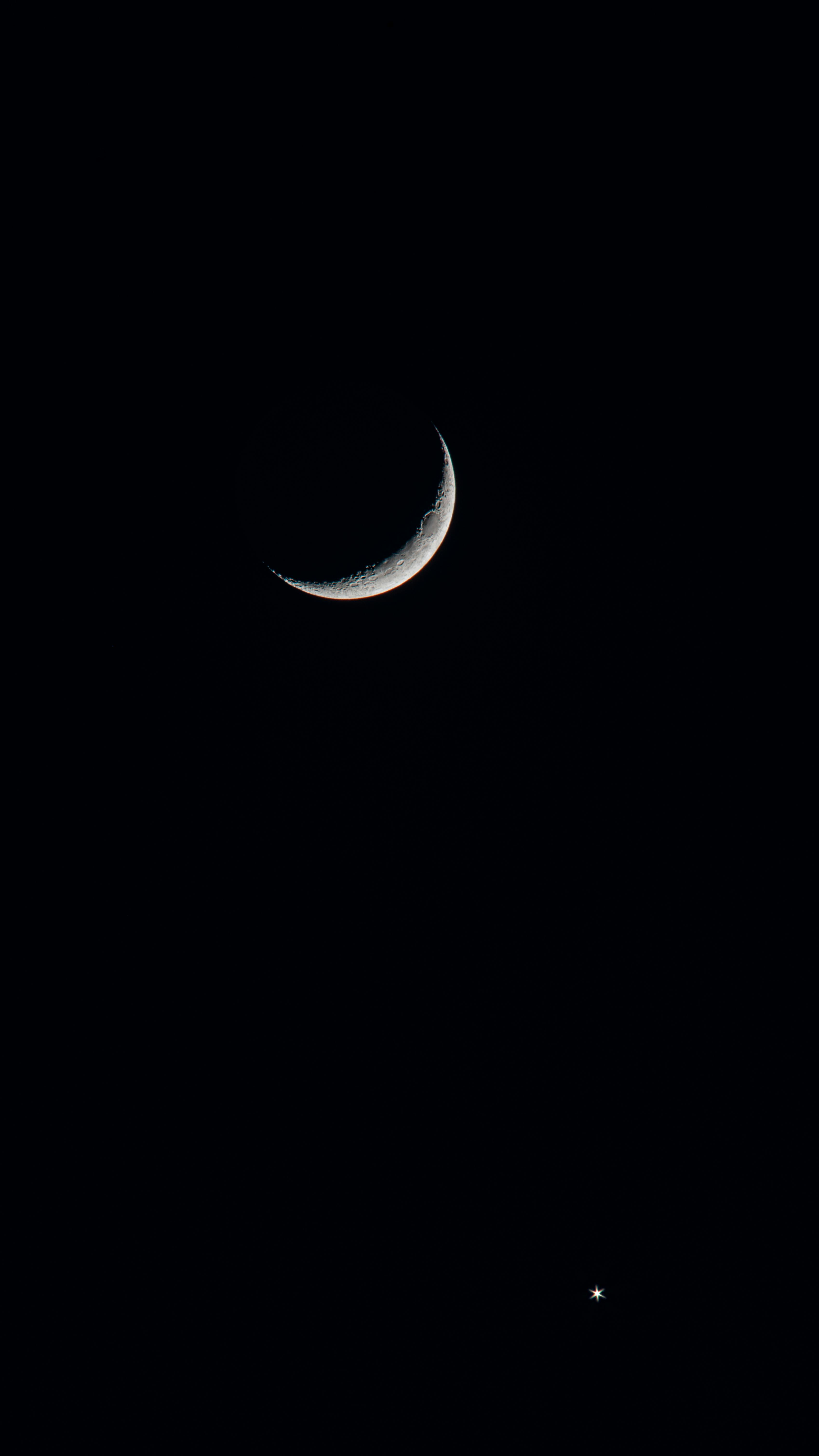 An enchanting crescent moon and a bright star against a dark night sky.