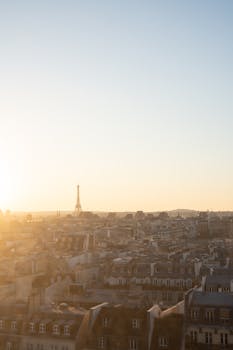 A tranquil aerial view of the Eiffel Tower at sunset, overlooking the Parisian rooftops.