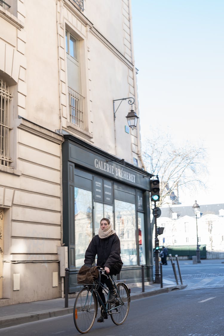 Woman In Jacket Cycling On Street In Paris