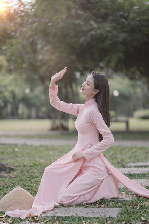 Woman Sitting in Pink Dress on Grass in Park