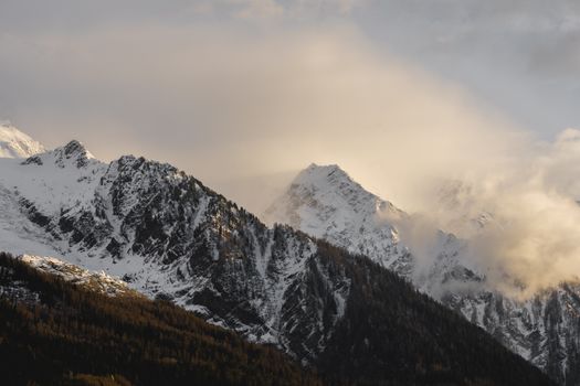 A stunning view of snow-covered mountains under a cloudy sky at sunrise.