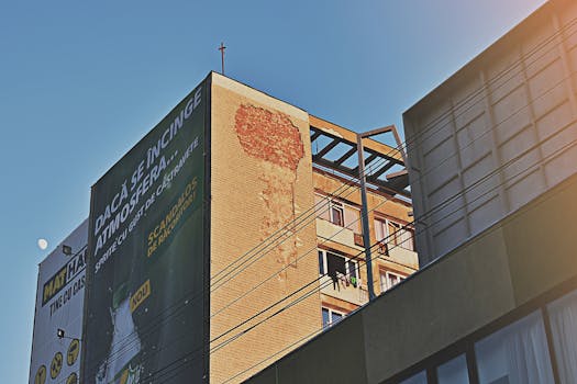 在城市中心，一座当代建筑与一个大型广告牌在晴朗的蓝天下矗立