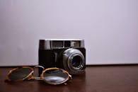 木桌上，一台经典的胶片相机与太阳镜的特写，展现出复古风格