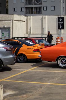 Vibrant orange cars parked in a city lot on a sunny day.