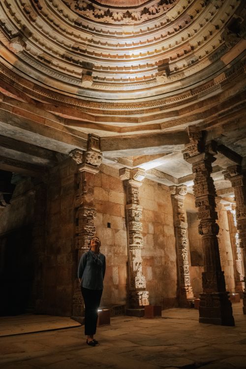 Free A woman standing inside an ancient temple, admiring the intricately carved columns and dome. Stock Photo