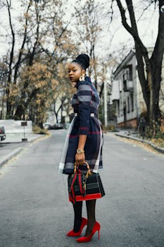 Stylish African American woman poses outdoors with handbag and red shoes.