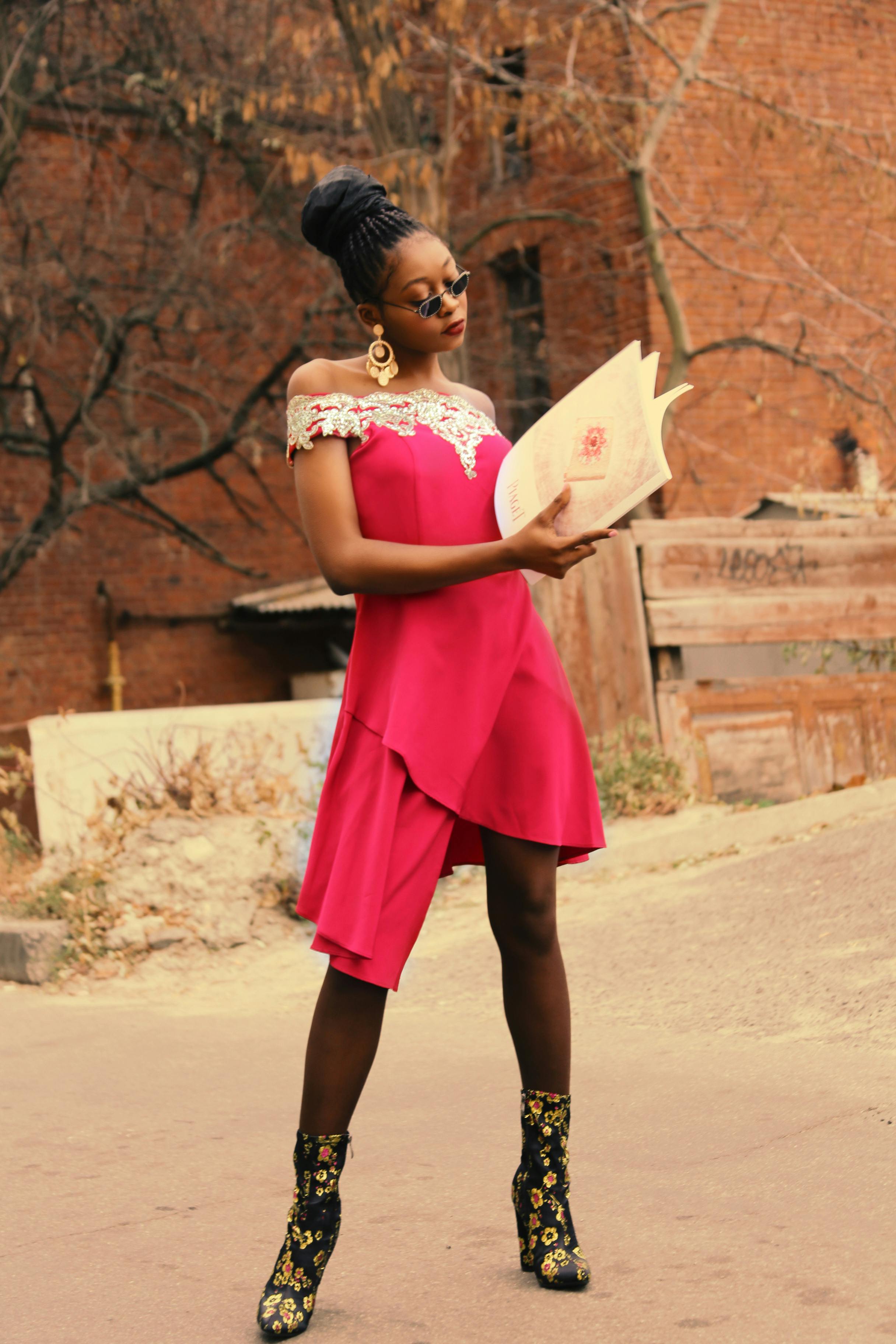 woman holding book while standing on concrete pavement