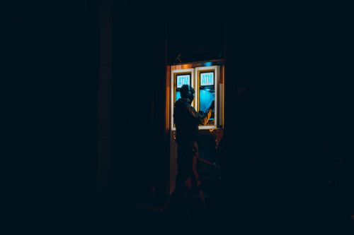 Free A man interacting with an ATM at night in a dark urban environment in Rotterdam. Stock Photo