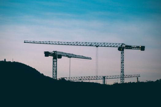 Silhouetted cranes against a twilight sky in Budapest, Hungary, showcasing modern construction.