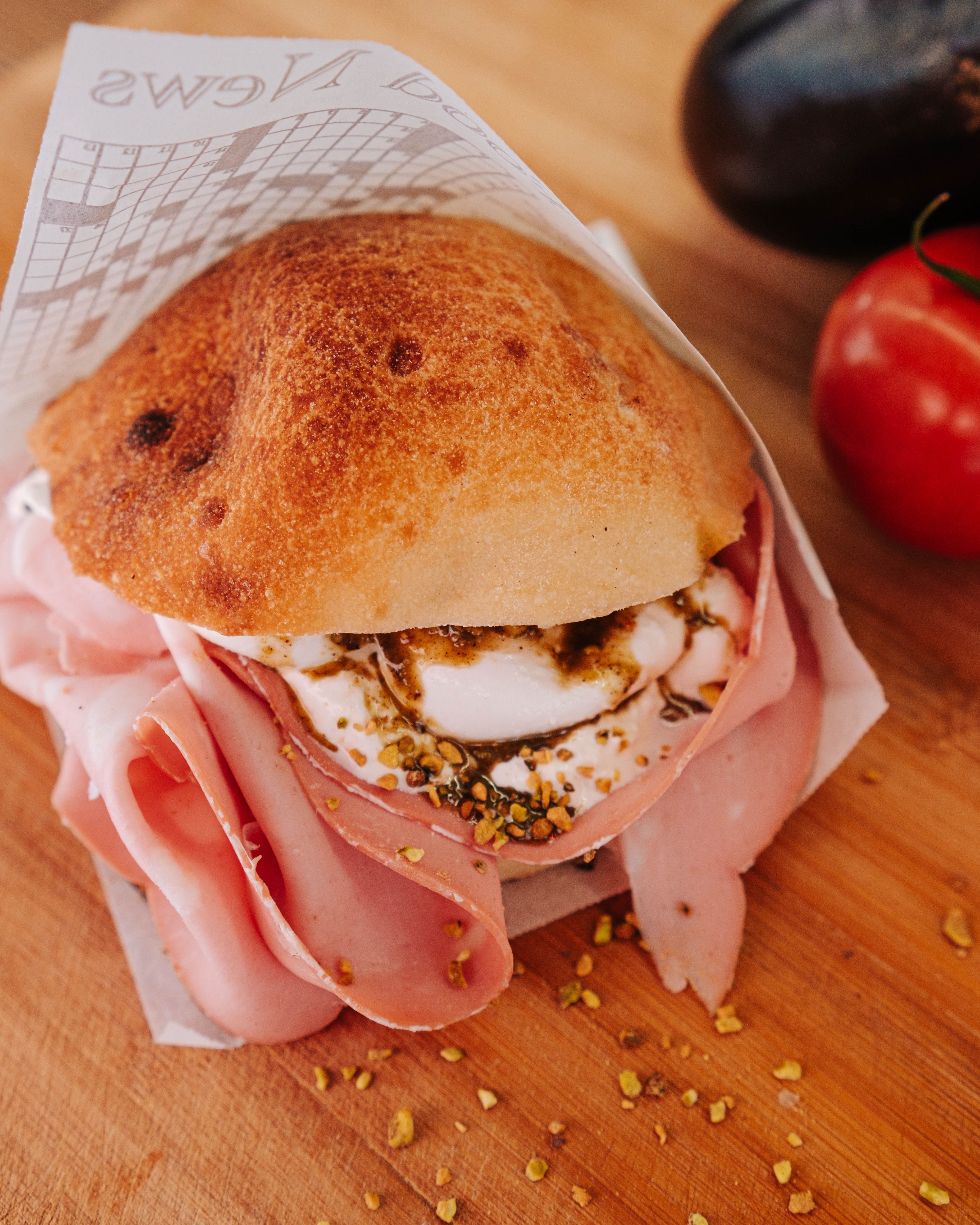 Delicious close-up of a mortadella sandwich with fresh cheese on a wooden board.