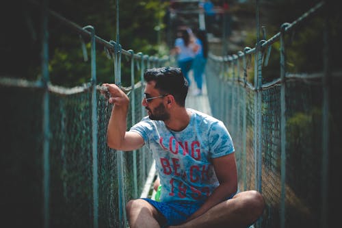 Man Sitting on Hanging Bridge