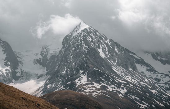 A stunning view of snow-capped mountain peaks in Obergurgl, Austria, shrouded by clouds.