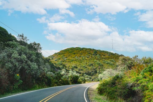 Photo of a Road with a View of a Green Hill 