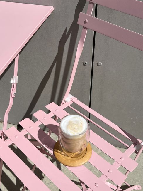 A glass of latte on a pink chair in an outdoor cafe, Tbilisi, Georgia.