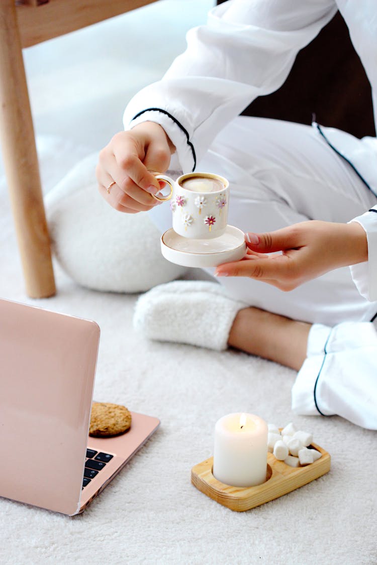 A Woman Sitting With A Cup Of Coffee In Front Of A Laptop