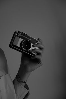 A nostalgic black and white photo of a vintage camera held by a hand.