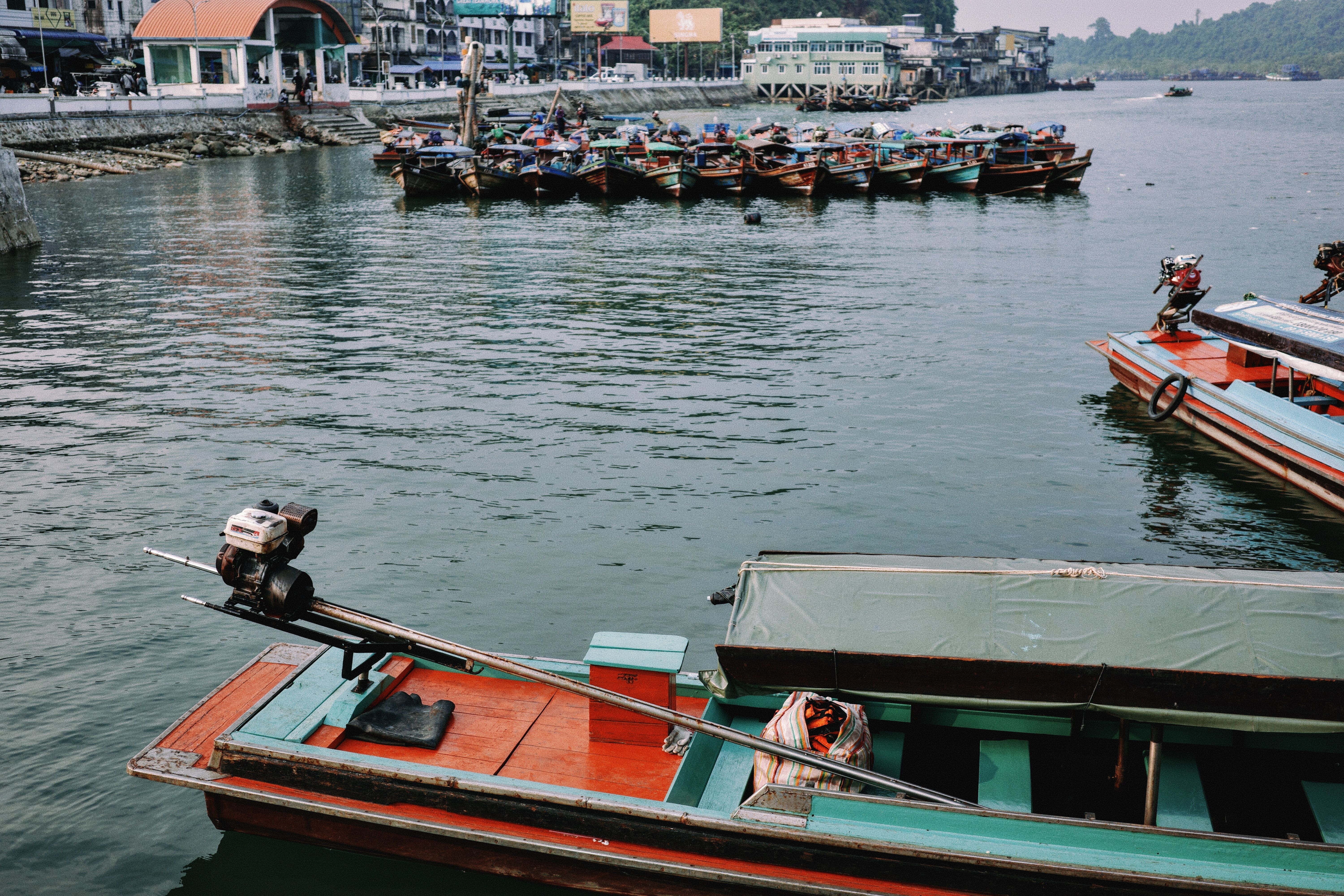 A vibrant scene of colorful fishing boats docked at a marina near coastal buildings.