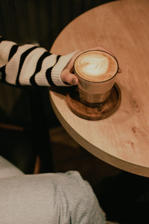 Free Close-up of a cappuccino on a wooden table with a cozy atmosphere. Stock Photo