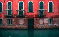 运河上矗立着优雅的威尼斯建筑，有着华丽的阳台和充满活力的红色外墙