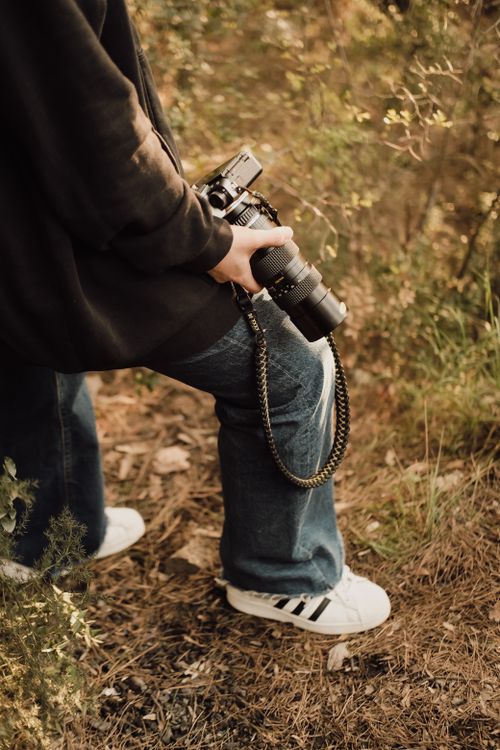 Free A person holding a vintage camera in an outdoor environment, wearing casual attire. Stock Photo