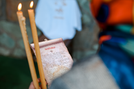 Close-up of a religious ceremony with lit candles and an Orthodox prayer scroll.