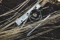 深色木质表面的干草中，放置着一台复古胶片相机的特写镜头，引人怀旧