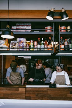 Baristas working behind a café counter with shelves stocked with ingredients.