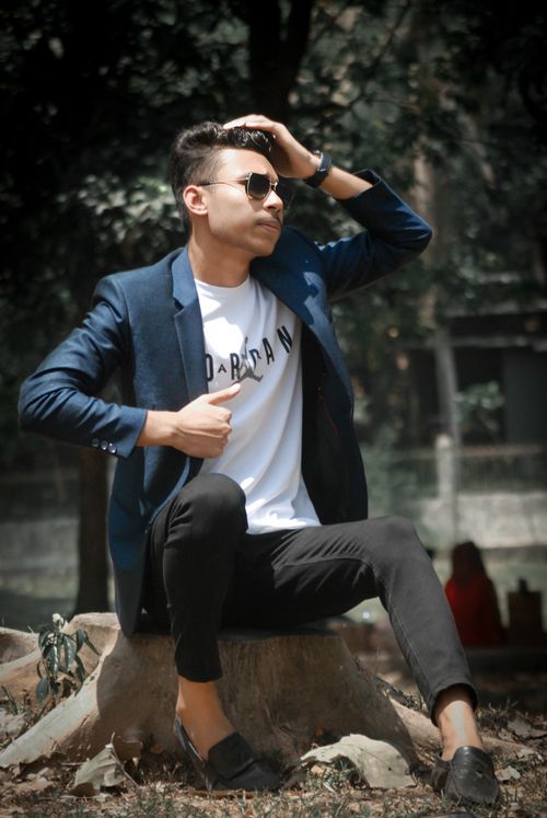 Free Fashionable man in sunglasses posing on a tree trunk outdoors. Stock Photo