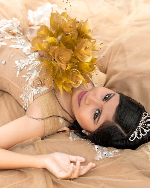 Free Brunette Woman in Dress and with Flowers Lying Down Stock Photo