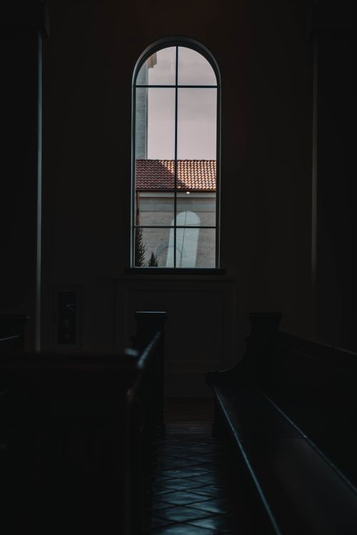 Free Dark and atmospheric church interior with an arched window view. Stock Photo