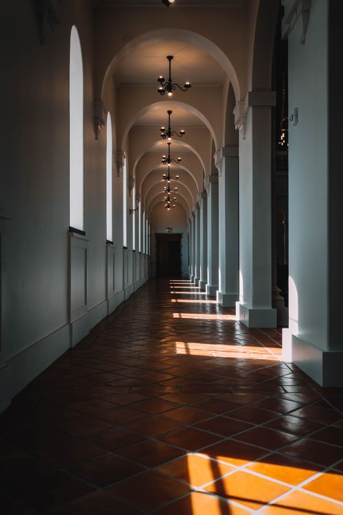 Free Explore the timeless beauty of a sunlit architectural corridor featuring arches and classic design elements. Stock Photo
