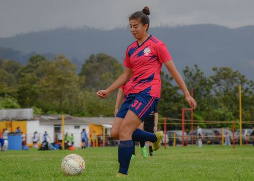 Free A young female soccer player in sportswear controls the ball on an outdoor field. Stock Photo