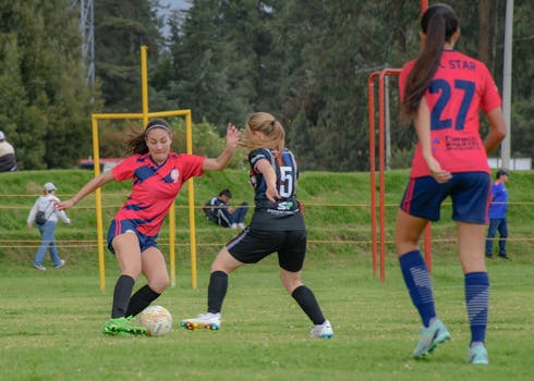 Dynamic moment of a women's soccer match in action on an outdoor grass field.