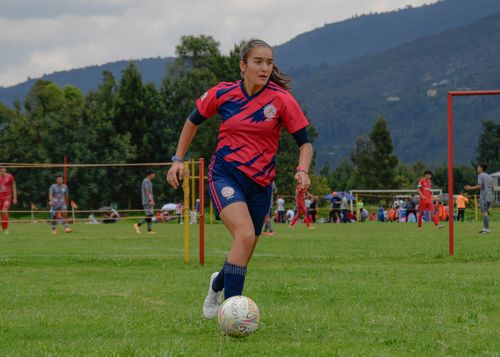 Free Focused young female soccer player dribbling on a lush green field during a daytime match. Stock Photo